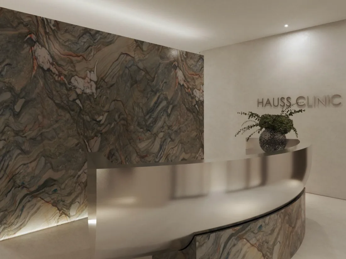 Reception at Hauss Clinic, with a marble wall and the clinic's name